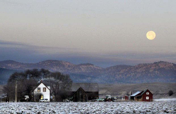 The full moon hangs over a farmhouse